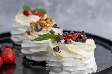 Pavlova meringue cakes with whipped cream and fresh strawberries, mint leaves. Selective focus.