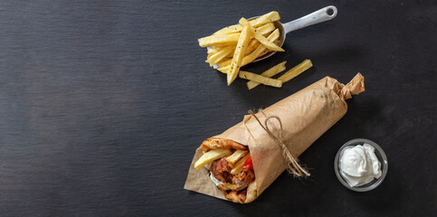 Gyro pita Shawarma wrap on black stone dish. Greek food with slice cut meat, overhead