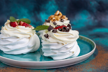Pavlova meringue cakes with whipped cream and fresh strawberries, mint leaves. Selective focus.