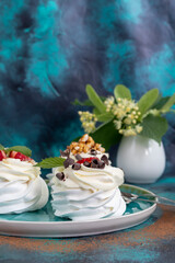 Pavlova meringue cakes with whipped cream and fresh strawberries, mint leaves. Selective focus.