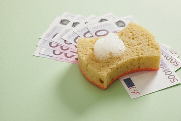 500 euro bill and sponge for washing dishes with foam, green background, money laundering, bad reputation