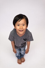 Boy wearing jeans and a gray tee in various poses, such as standing or sitting on a chair