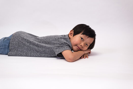 Boy Wearing Jeans And A Gray Tee In Various Poses, Such As Standing Or Sitting On A Chair