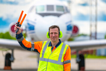 Portrait of a technician - a ground crew in a signal vest waiting for the aircraft to taxi to the...