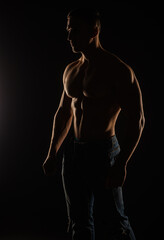 Fototapeta na wymiar Silhouette of topless guy posing in studio while standing