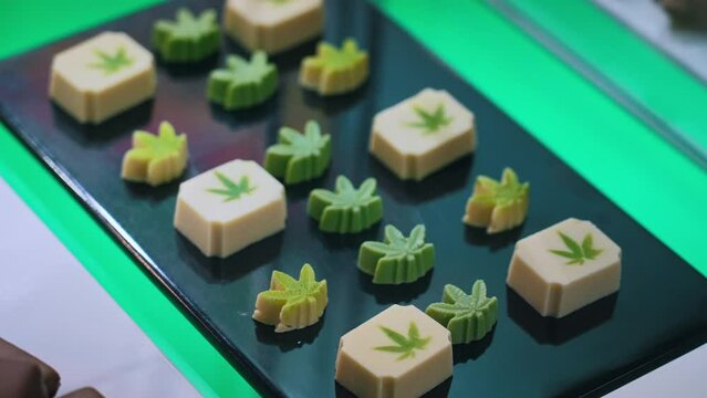 Cute green and white weed sweets in the shape of marijuana leaves. Cannabis CBD CBG. High quality 4k footage