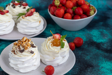 Pavlova meringue cakes with whipped cream and fresh strawberries, mint leaves. Selective focus.