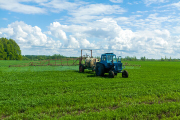 Obraz premium Agricultural machinery, Tractor and farmer in agricultural fields of wheat and rapeseed and dramatic clouds, New tractors in the field - stock photo, Combine harvester in a wheat field, Sprayer
