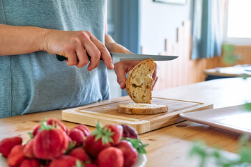 Woman making summer strawberry sandwich. Female hands cutting bread for toast. Healthy eating, fruit dieting brunch.