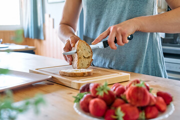 Woman making summer strawberry sandwich. Female hands cutting bread for toast. Healthy eating, fruit dieting brunch.