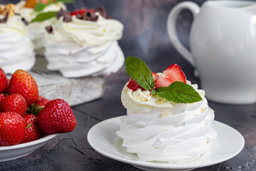 Pavlova meringue cakes with whipped cream and fresh strawberries, mint leaves. Selective focus.