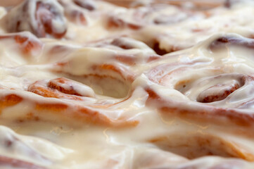 Closeup of several cinnamon buns.Beautiful fresh cinnamon rolls close-up on wooden grunge texture table. Fragrant homemade cakes, Cinnabon. A Cup of tea on a white saucer, cinnamon sticks.