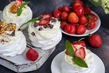 Pavlova meringue cakes with whipped cream and fresh strawberries, mint leaves. Selective focus.