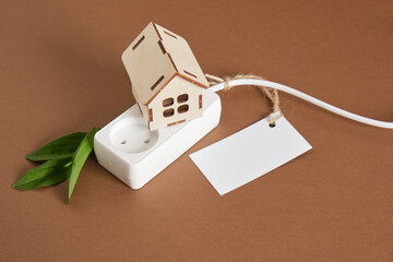 wooden house model, network filter with sockets and leaf, tag for logotype and test, copy space, eco energy concept - obrazy, fototapety, plakaty