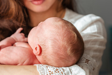 Newborn baby in mom's arms at home, mother hugs baby