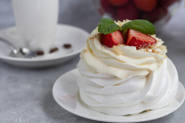 Pavlova meringue cakes with whipped cream and fresh strawberries, mint leaves. Selective focus.