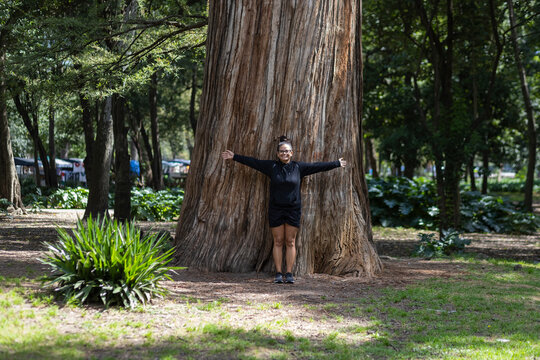 Woman with open arms on the trunk of a large tree in Chapultepec Park