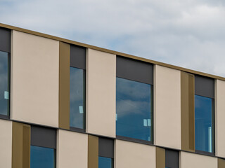 Modern building architecture. Exterior of a contemporary building with beige elements and windows on the facade. New office house in the city with a minimalistic business style.