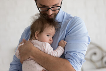 Caring father holds on arms, calming his cute baby, embracing with love enjoy moments of tenderness, express caress and affection, feels happy being father, close up. Fatherhood, family bond concept