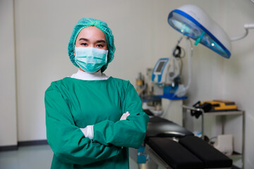 Fototapeta na wymiar Portrait of Asian woman Surgical doctor wearing face mask and arms crossed standing in Operating Theater ward at modern medical center.