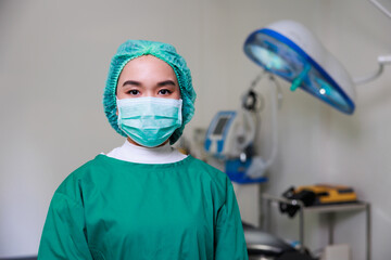 Fototapeta na wymiar Portrait of Asian woman Surgical doctor wearing face mask standing in Operating Theater ward at modern medical center.