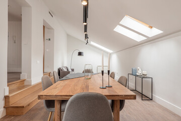 Dining room with natural wood table with steps leading to another room, skylights in the sloping...