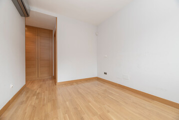 Fototapeta na wymiar Empty room with built in oak wardrobe, gray air conditioner and light oak floor