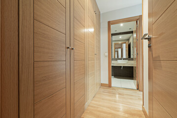 Dressing room with oak wood doors with access to en-suite bathroom with cream marble top