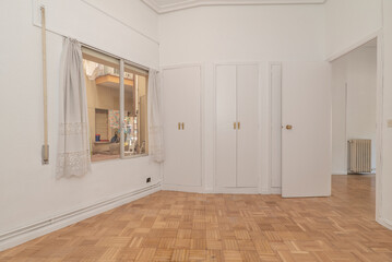 Empty living room with oak parquet and white carpentry, oak parquet floor, three-body built-in...