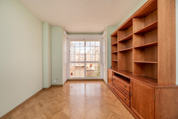 Empty living room with oak parquet floor with glass and white aluminum bay window and cherry wood bookcase
