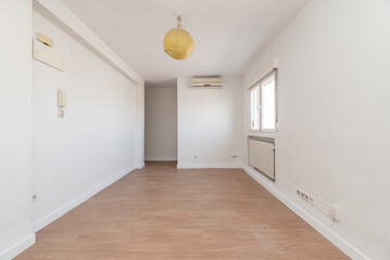 Empty apartment with a light wooden floor, a window to the side, a radiator in a niche below the...