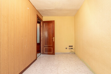 Empty room with ceramic stoneware floor and walls painted in light yellow and PVC tongue-and-groove