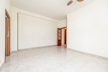 Empty living room with ceramic tile floors, dark woodwork and ceiling fan