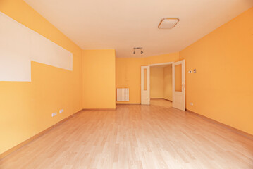 Empty living room with peach painted walls, white woodwork and light wood floor