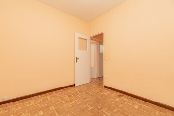 Room with white wooden door with skylight, parquet floor and brown baseboards