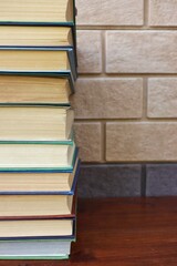 glasses and a stack of books lie on a brown wooden table