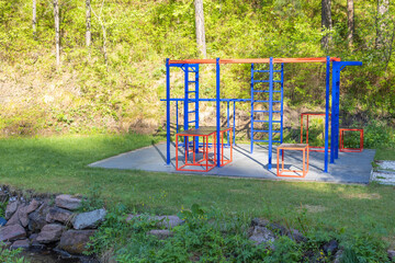 Empty sports ground with exercise equipment on a sunny meadow in a summer forest