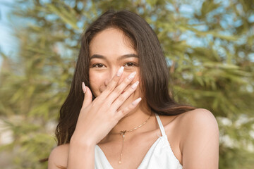 A pretty Filipino woman blushing while flirting with someone. Signs of physical attraction during a date. Reaction from flattery.