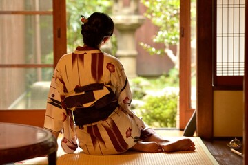 京都町屋の和室に座りたたずむ浴衣を着た若く美しい女性の後ろ姿