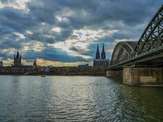 Cologne Cathedral and Hohenzollern bridge on Rhine river during a cloudy sunset, Germany