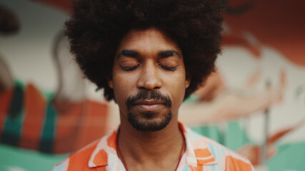 Close-up frontal portrait of  young African American man opens his eyes looks at the camera and...