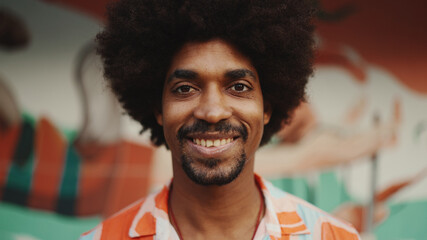 Close-up frontal portrait of  young African American man opens his eyes looks at the camera and...