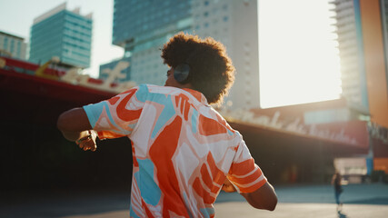 Close-up of cheerful young African American man wearing shirt listening to music in headphones and...