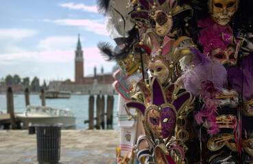 Venetian carnival mask souvenirs in street shop in Venice, Italy against famous blurred san giorgio maggiore church in the background