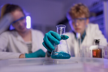 Science students doing chemical experiment in the laboratory at university, close-up.
