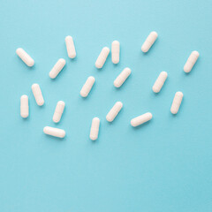 White capsule pills on a blue background. Medical background with copy space for text.	