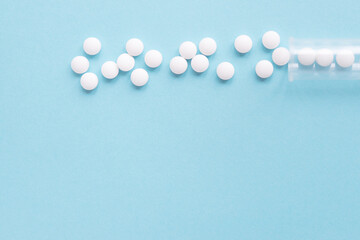 Different white pills and a plastic container on a blue background. Medical theme.	