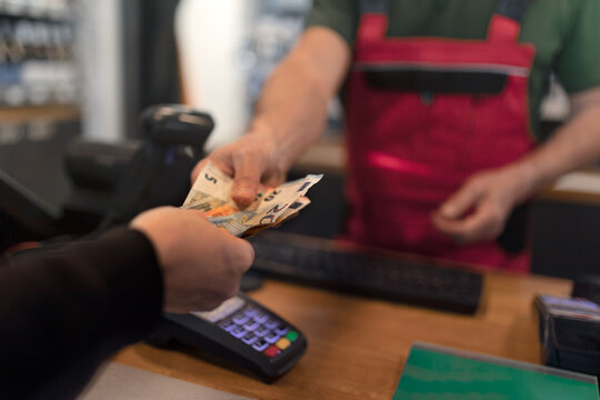 Employee taking cash payment from costumer in gas station, close-up