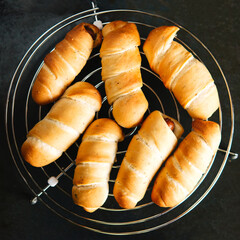 Sausage in dough - fresh baked goods, snacks. Delicious sausage rolls on black metal background	