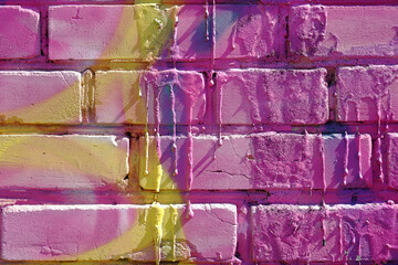 Textured background of a brick street wall painted in bright purple colors with yellow streaks and...